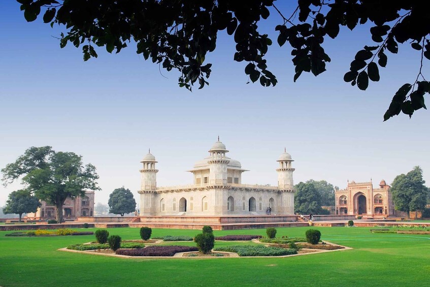 A large white building with domes and towers, surrounded by a well-manicured garden and a smaller building with arches. 3