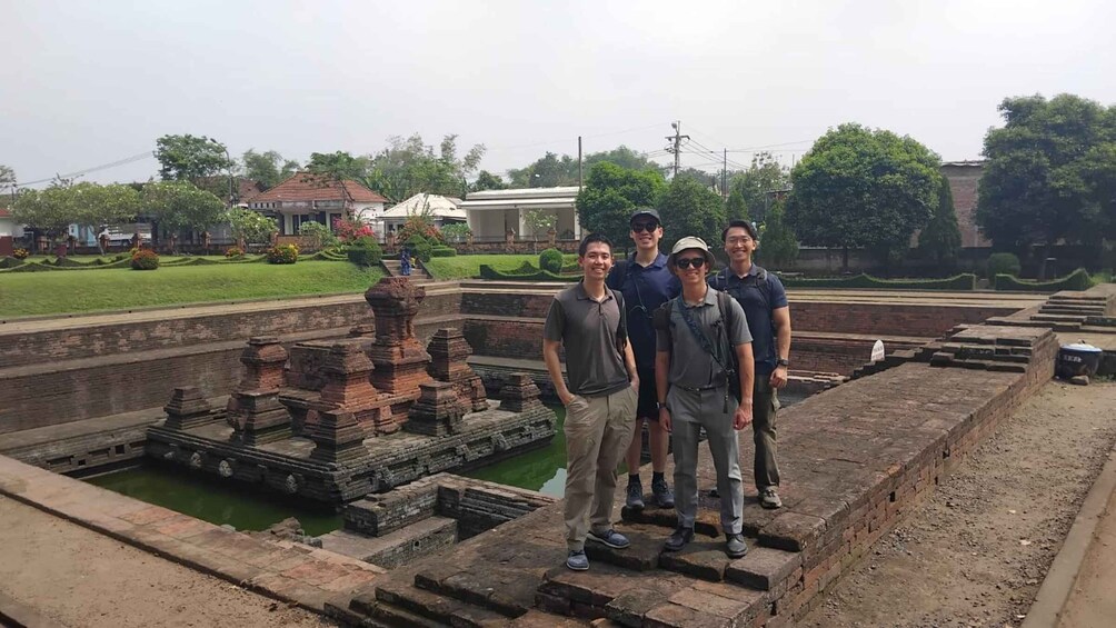 A group of people standing on ancient stone structures with a water feature in the background. 3
