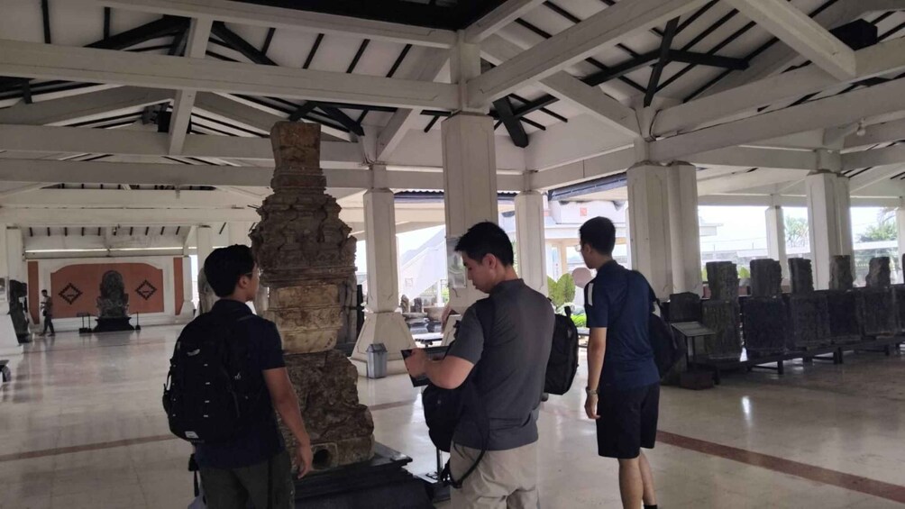 A covered area with stone pillars, a tiled floor, and a few people standing and looking around. 5
