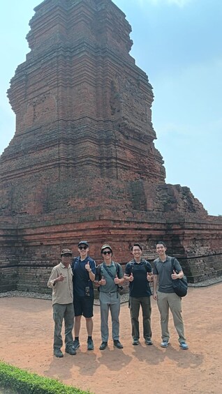 A group of people standing in front of a large, ancient brick structure. 2