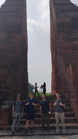 A group of people standing in front of ancient brick structures. 4