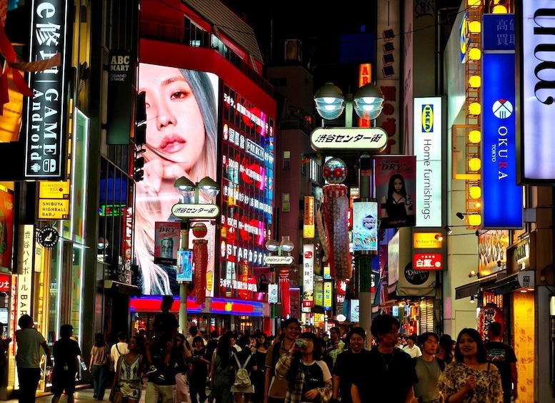 A busy urban street at night with neon signs and advertisements. 5