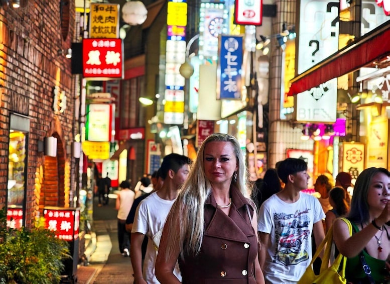 A bustling street with neon signs and brick buildings. 2
