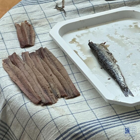 A white tray with fish and fish skin on a checkered cloth. 2
