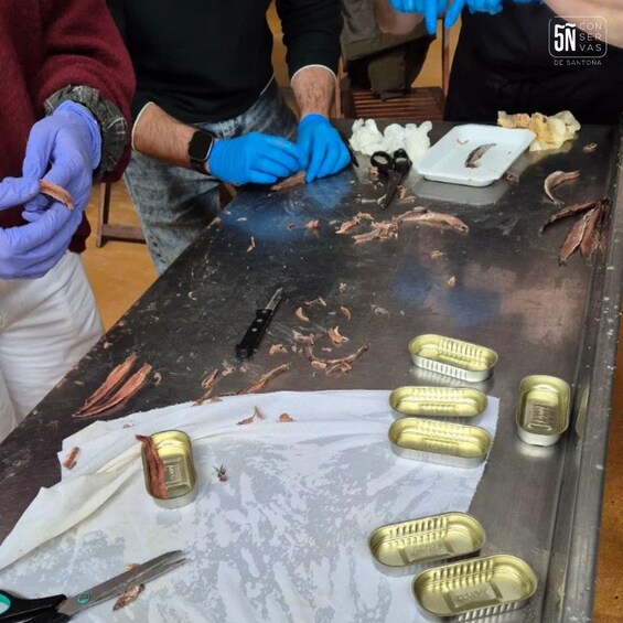 A person preparing food, with a cutting board, scissors, and canned goods on a table. 3