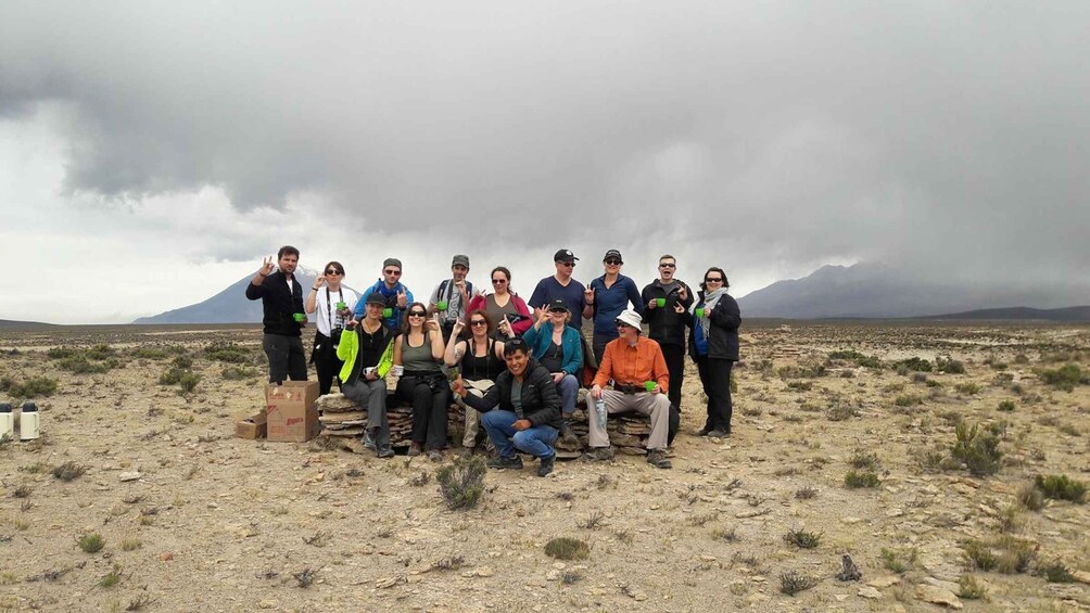 A group of people posing in a desert landscape with a mountain in the background. 5