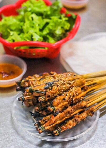Skewered grilled meat with sesame seeds, accompanied by a side of lettuce and a small bowl of sauce. 5