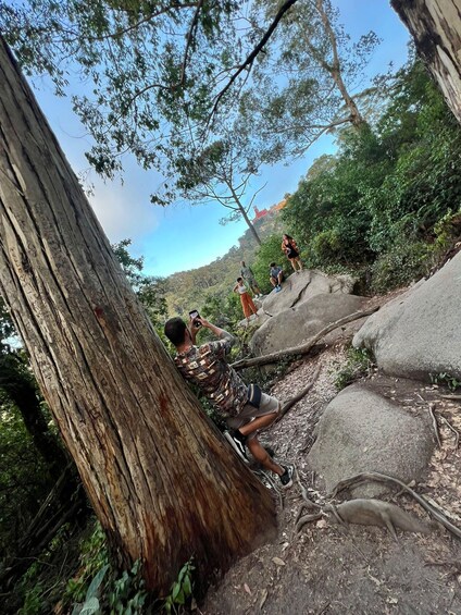 A group of people hiking on a rocky trail surrounded by trees. 5