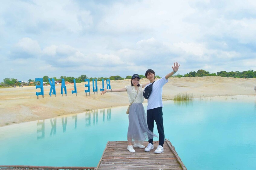 Two people standing on a wooden platform with arms outstretched over a body of water. 1