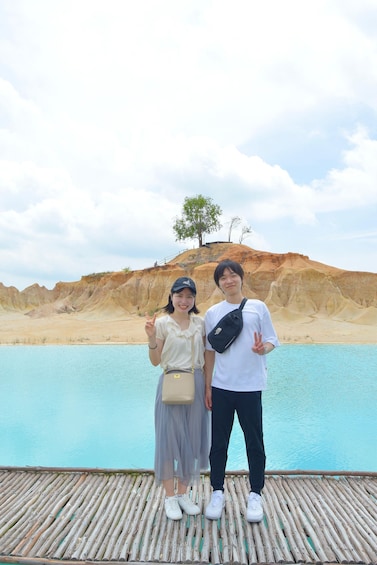 Two people standing on a wooden dock by a body of water with a rocky landscape in the background. 5