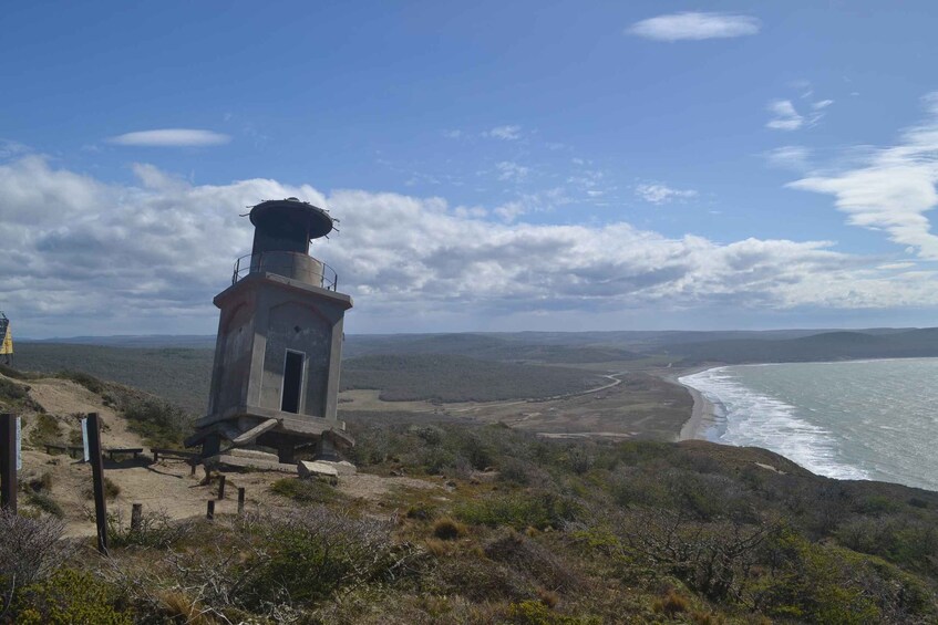 A coastal viewpoint with a small tower, sandy beach, and ocean waves. 2