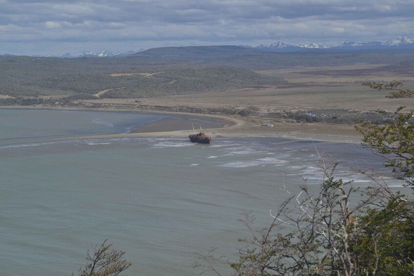 A ship stranded on a beach with mountains in the background. 5