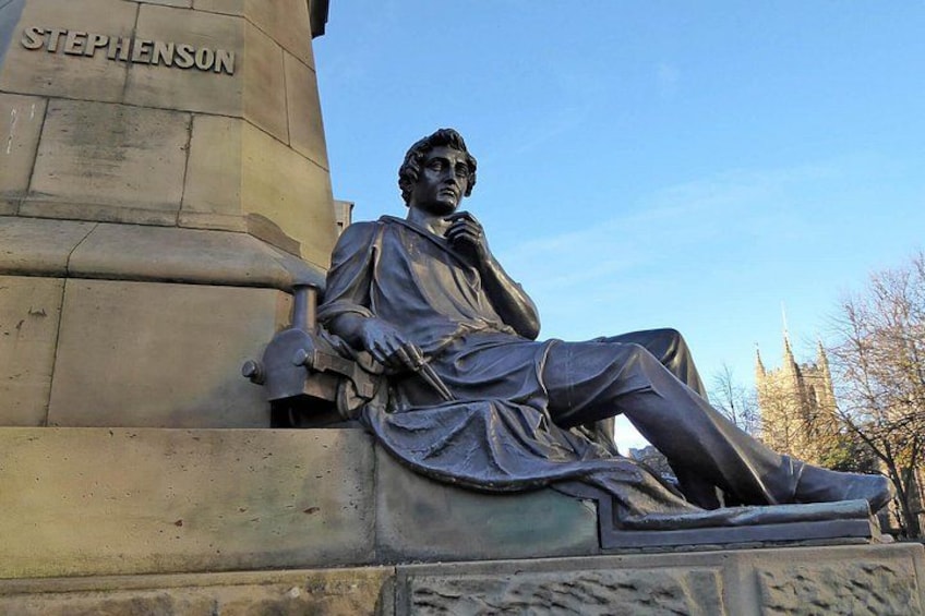 A statue of a seated man with a book, labeled 'Stephenson,' on a stone pedestal. 2