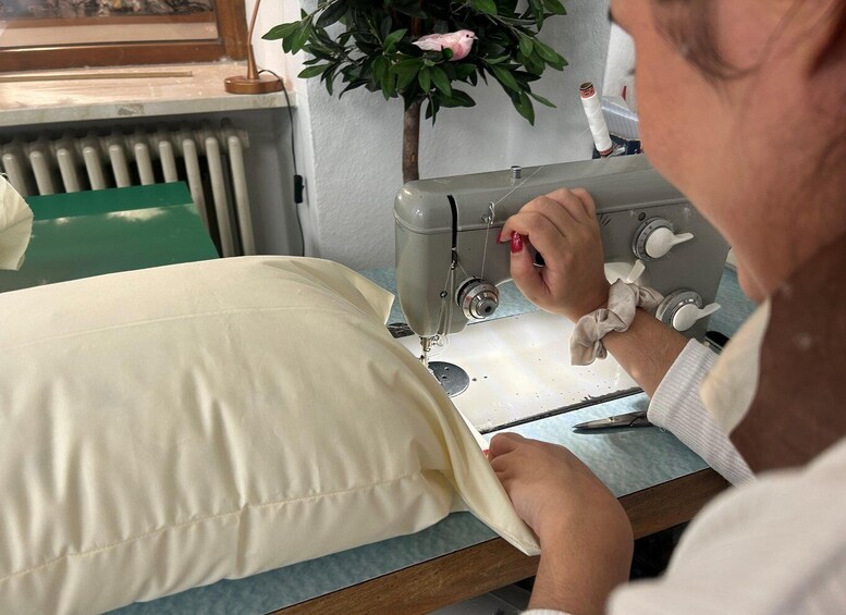 A person sewing a pillow on a sewing machine. 4
