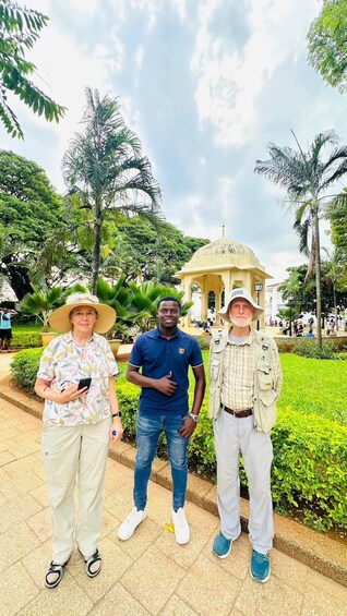 Three people standing in a park with palm trees and a gazebo in the background. 4