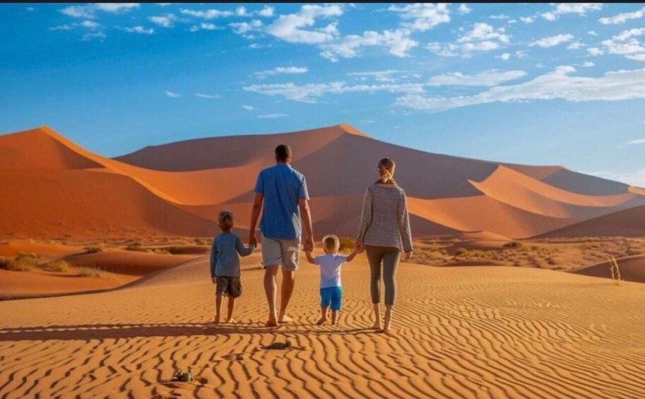 A family walking on a desert with sand dunes and a clear sky. 1