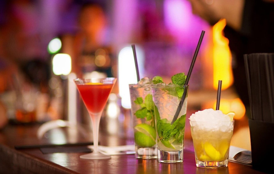 Three cocktails on a bar counter with a blurred background. 3