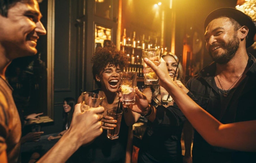 People toasting with drinks in a dimly lit bar. 5