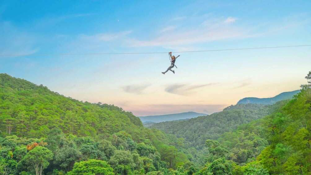 A person bungee jumping over a lush green valley with mountains in the background. 2