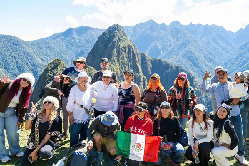 A group of people posing with a flag in front of a mountain range. 2