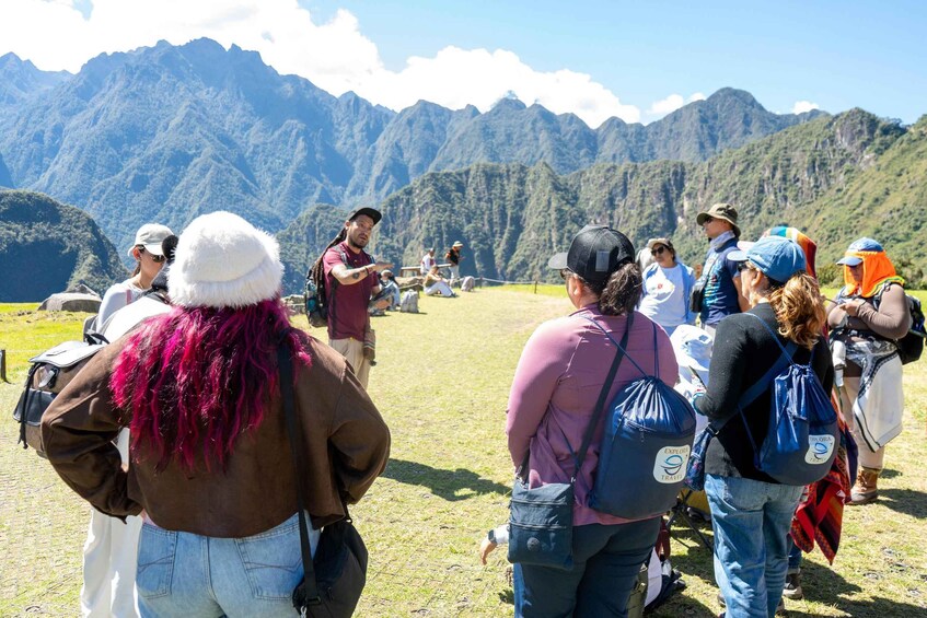 A group of people standing on a grassy field with a mountainous landscape in the background. 5