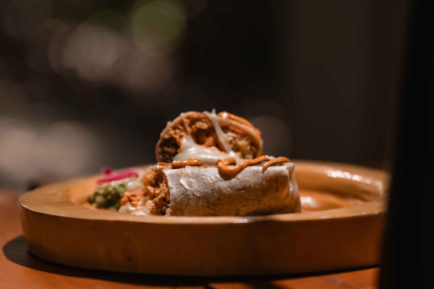 A burrito with a sauce drizzle on a wooden plate. 4