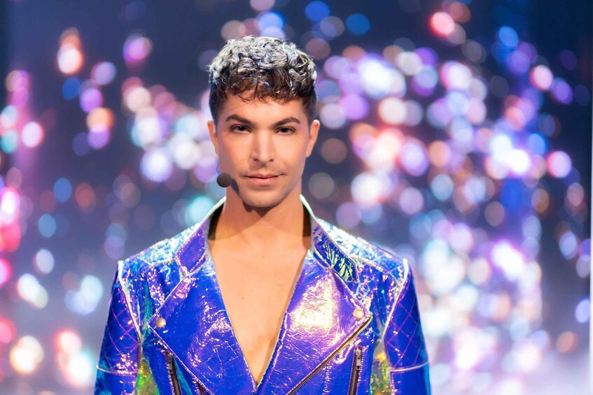 A person in a shiny blue jacket with a zipper and a microphone. 2