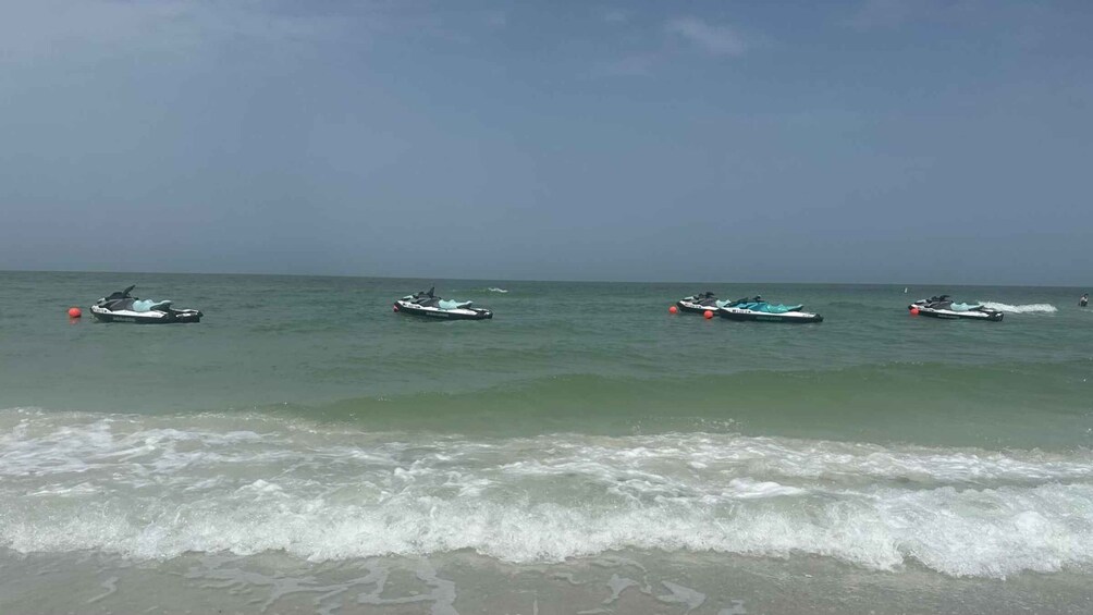 Four jet skis on calm ocean waters near a beach. 3