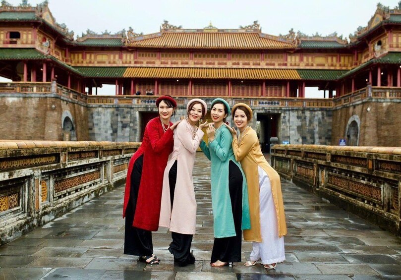 A group of people standing on a bridge with a traditional building in the background. 1