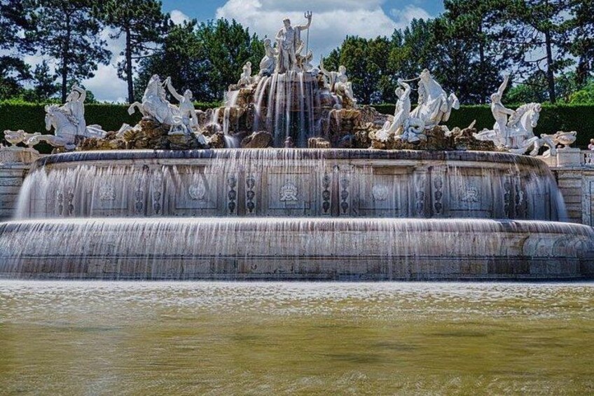 A multi-tiered fountain with statues, surrounded by trees. 3