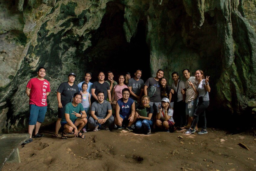 A group of people posing in front of a cave entrance. 2