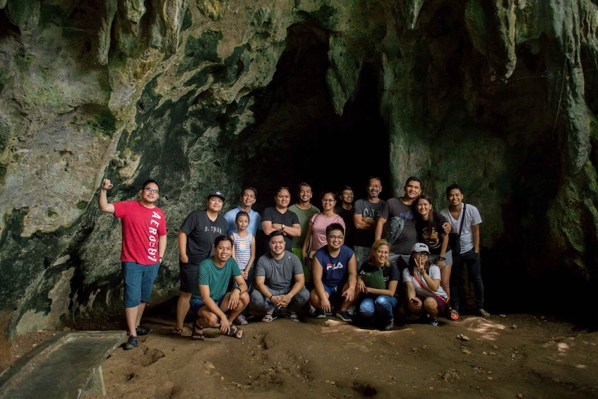 A group of people posing in front of a cave entrance. 3
