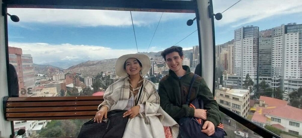 Two people sitting on a bench with a cityscape and mountains in the background. 5
