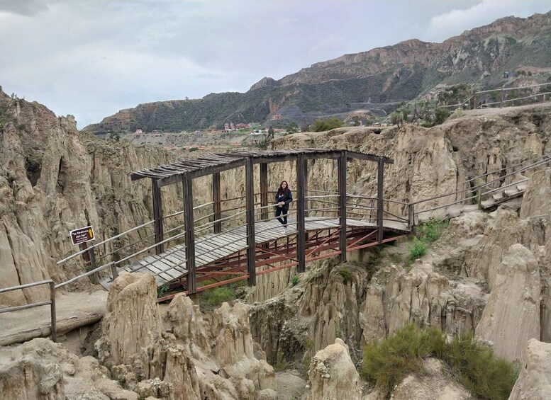 A metal bridge with a metal railing in a rocky canyon with a mountain in the background. 4