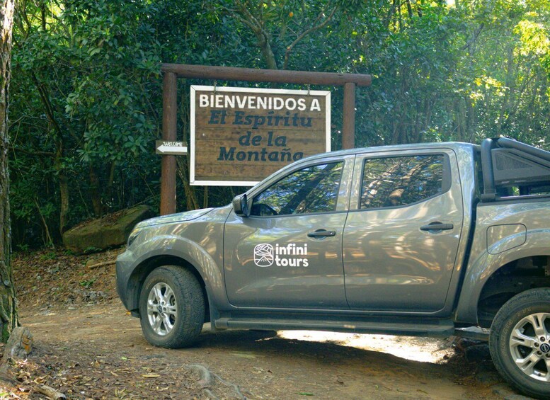 A vehicle parked in front of a sign welcoming visitors to El Espíritu de la Montaña. 4