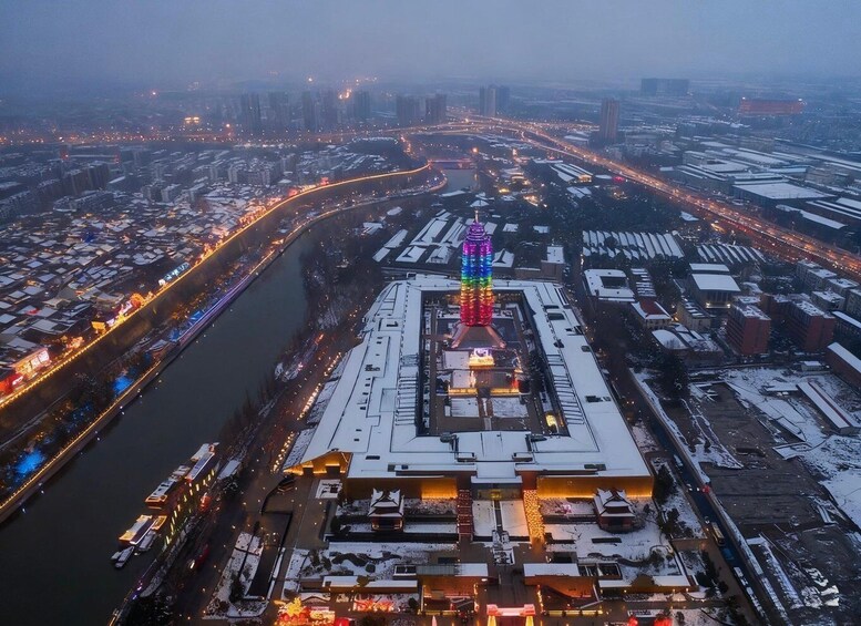 An aerial view of a cityscape with a prominent building featuring a colorful tower. 4