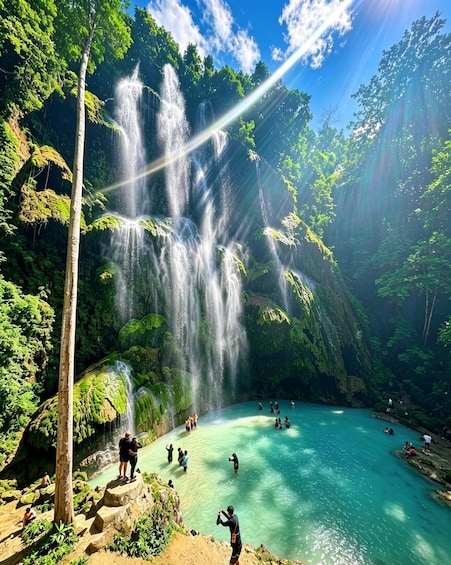 A waterfall cascading into a turquoise pool surrounded by lush greenery. 2