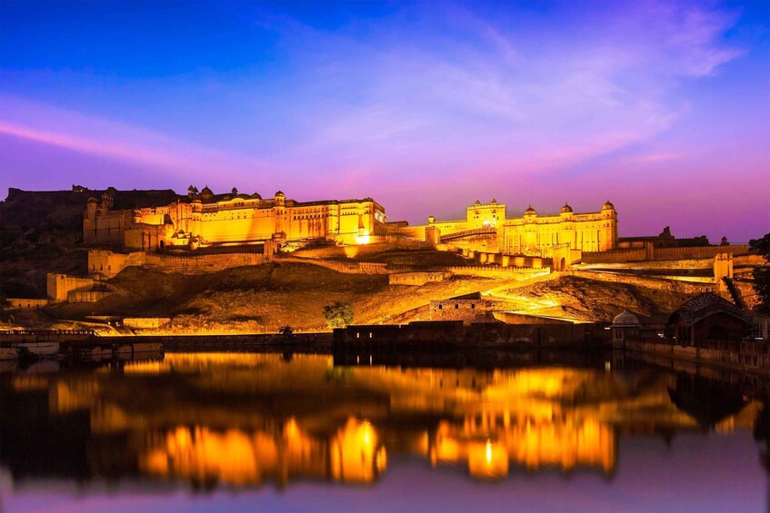 A large, illuminated fort with a reflection in the water. 4