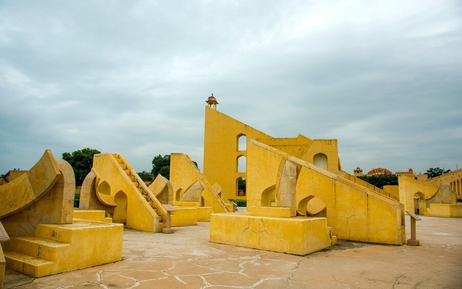A large, yellow, ancient structure with arches and staircases. 5