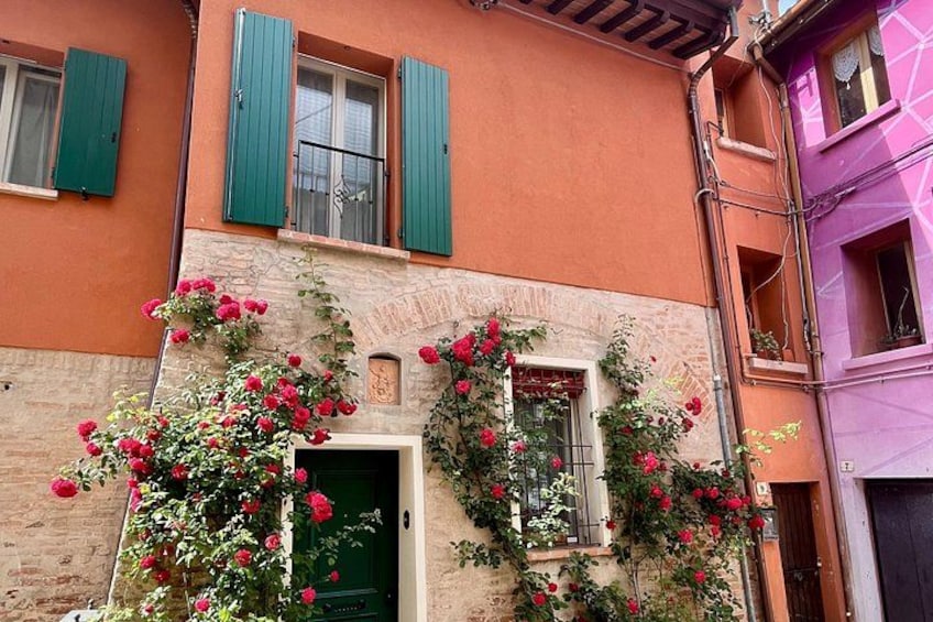 A building with green shutters, a stone facade, and red flowers. 1