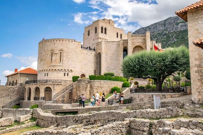 A historic stone fortress with a round tower, arched windows, and a staircase leading to the entrance. 2