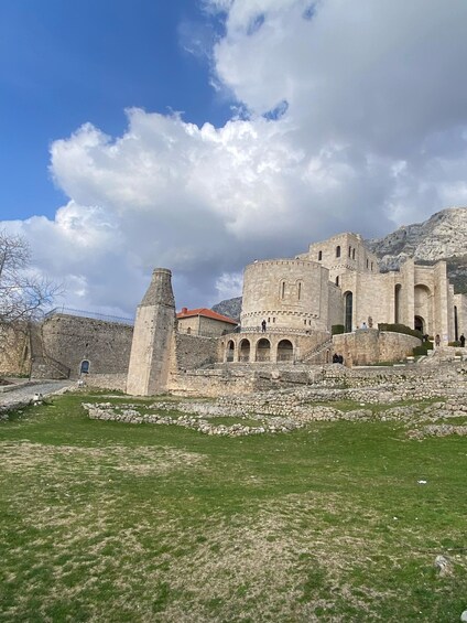 An ancient stone fortress with a prominent tower, surrounded by a grassy area and a stone wall. 4