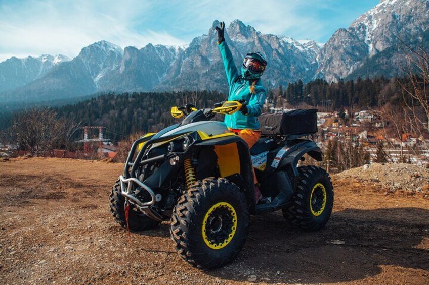 A person on an ATV in a mountainous area with snow-capped peaks in the background. 3
