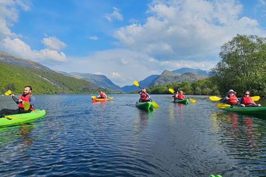 People kayaking on a calm lake with mountains in the background. 1