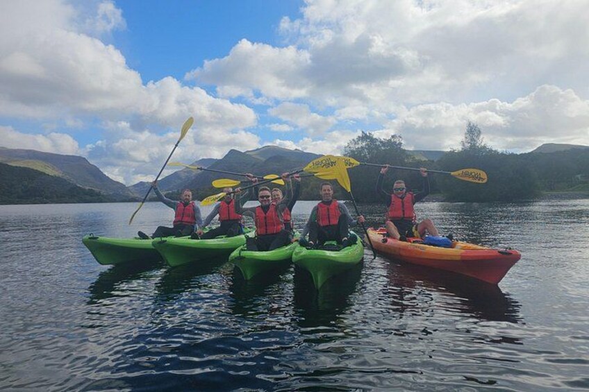 A group of people kayaking on a calm lake with mountains in the background. 4