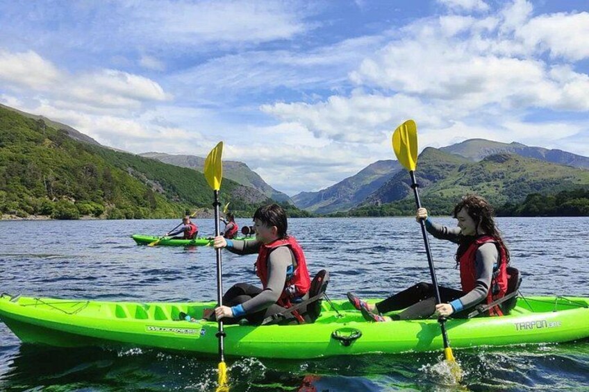 Two people kayaking on a lake with mountains in the background. 3