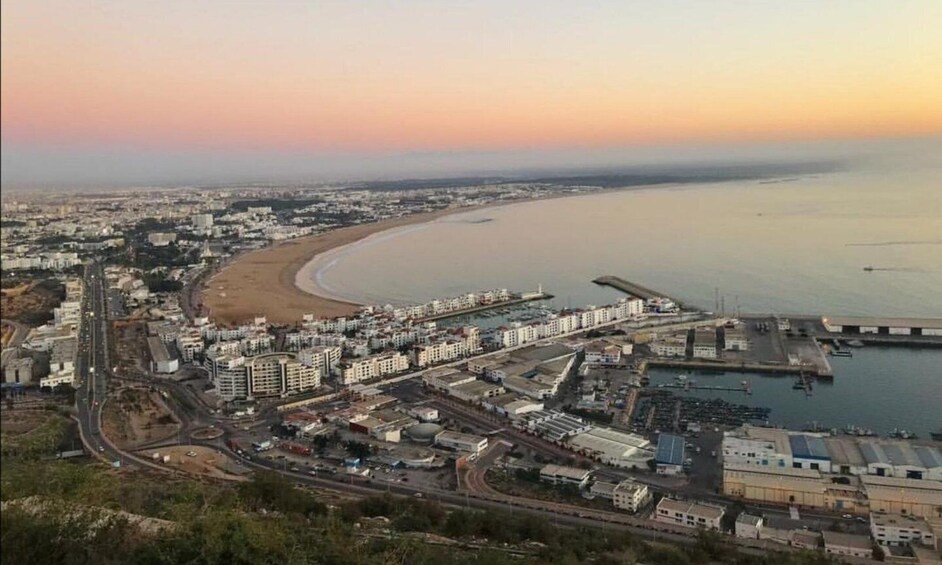 A coastal cityscape with a beach, industrial area, and a bridge. 3