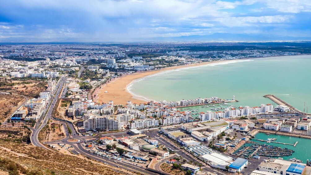 A coastal cityscape with a beach, marina, and dense urban development. 5