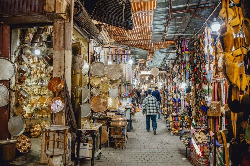 A bustling market with various stalls selling cookware, textiles, and footwear. 2