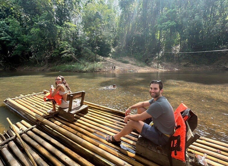 Two people on a bamboo raft in a river surrounded by dense forest. 3